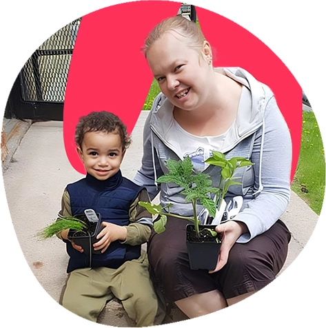 Une femme et un garçon souriant tenant chacun une plante.