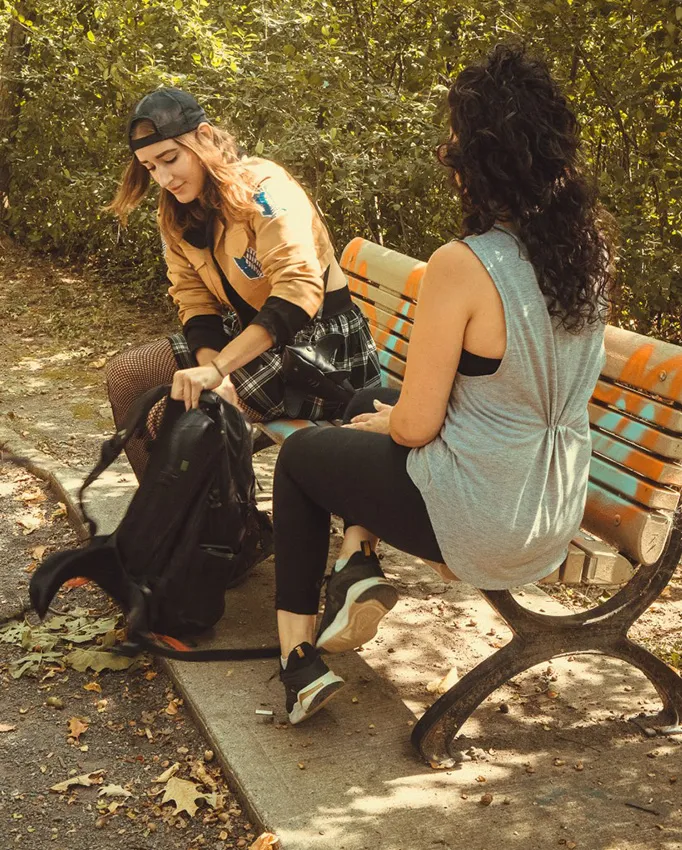 2 jeunes femmes assises sur un banc de parc.