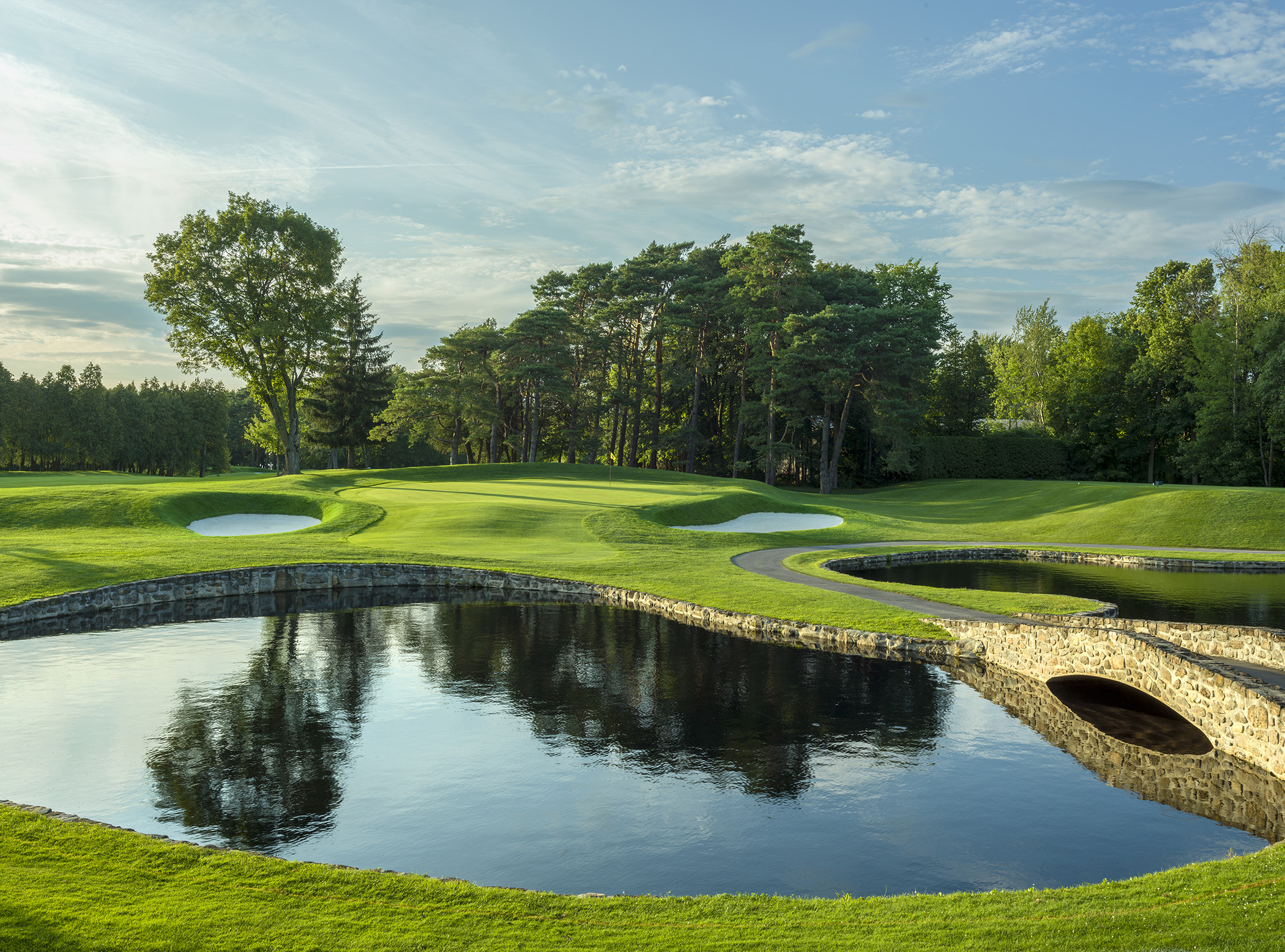 Le Club de golf Laval. Un champ vert avec un lac au centre.