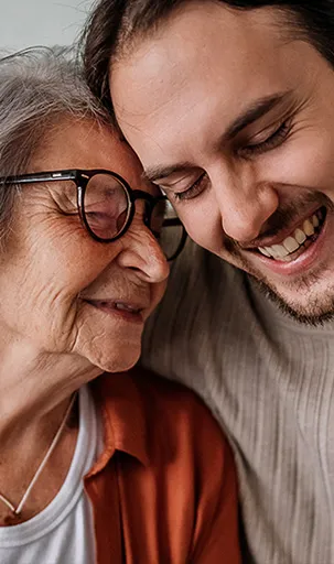 Dame de plus de 80 ans embrassant affectueusement son petit-fils adulte.