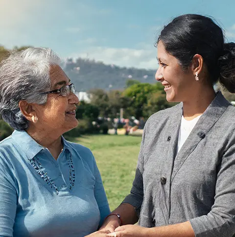 Une jeune femme tenant la main d'une vieille femme et souriant en signe de respect.