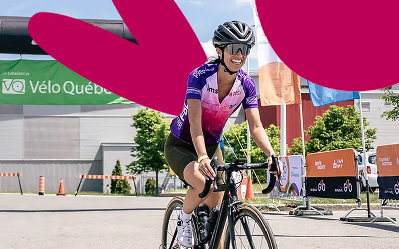 Une femme souriante sur un vélo participant à l'activité Pédalons pour l'inclusion de Mission inclusion.