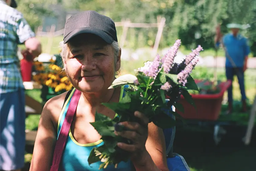 Femme avec un foulard jaune sur la tête et souriante tenant de nombreux haricots.