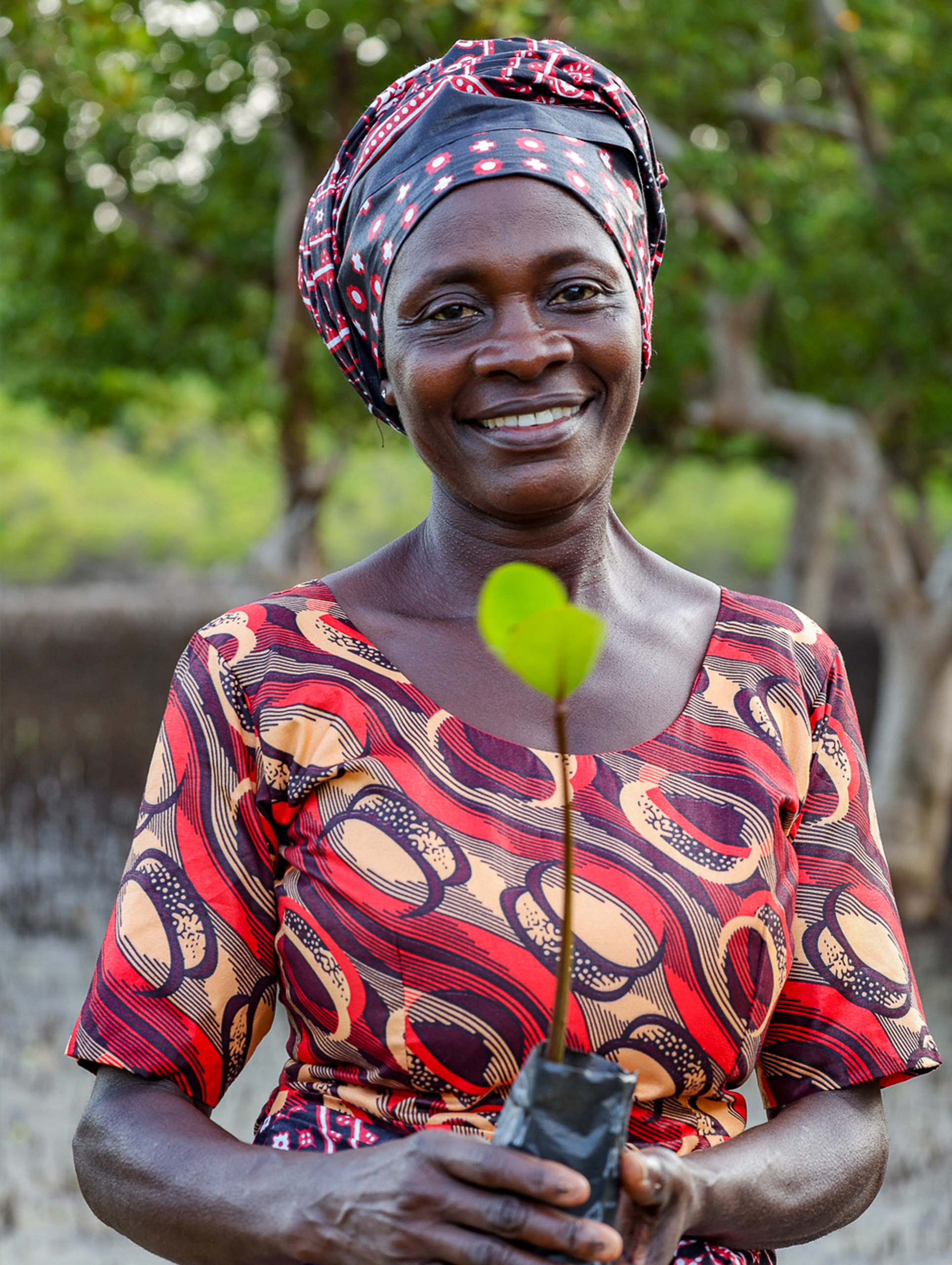 une main tenant de la nourriture pour poissons devant un étang de pisciculture.