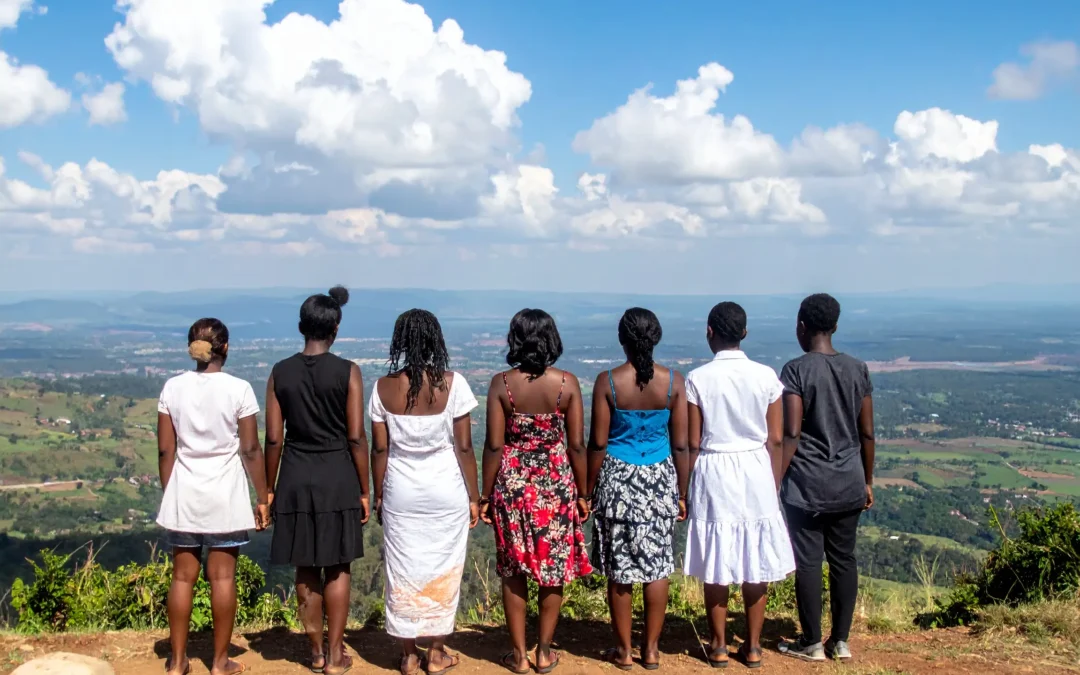 Cinq Kényanes au sommet d'une montagne au Kenya, la nature s'étendant à leurs pieds. Elles sont de dos à l'objectif, le regard tourné vers l'horizon.