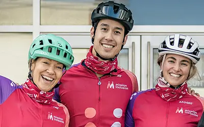 Trois personnes souriantes vêtues de vêtements de cyclisme.