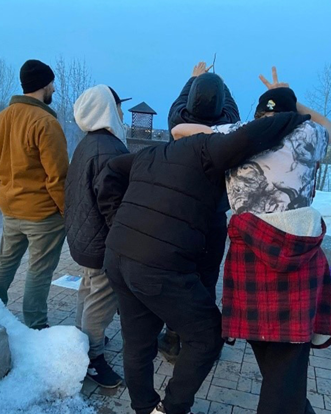 Quatre jeunes gens, dos à dos, enlacés, contemplant l'horizon.